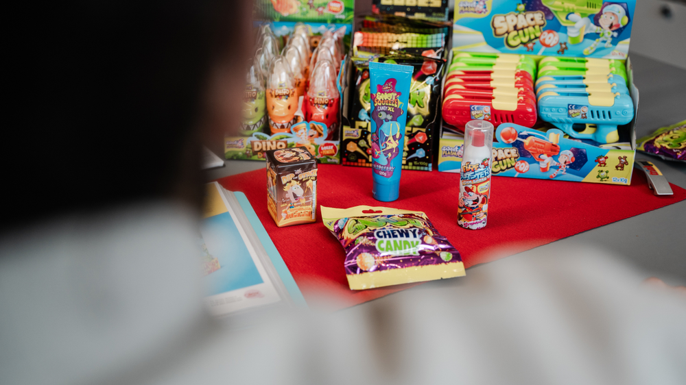 Ein Tisch mit bunten S&uuml;&szlig;igkeiten und Spielzeug, darunter Geister-S&uuml;&szlig;igkeit, Chewy Candy, und Space Guns.