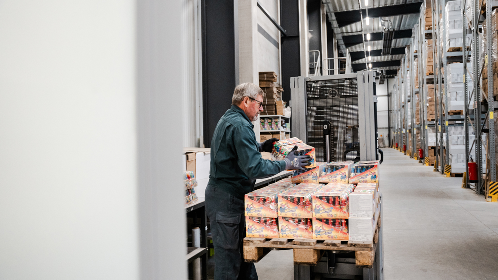 Un addetto al magazzino impila i prodotti su un pallet.